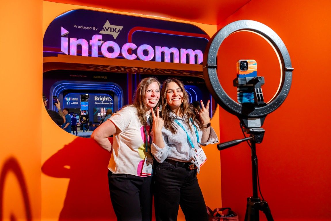 Two team members taking a selfie together in front of the InfoComm enterance 