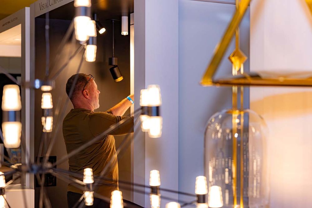 A Lightapalooza attendee looks at lighting tech in a booth with a modern chandelier