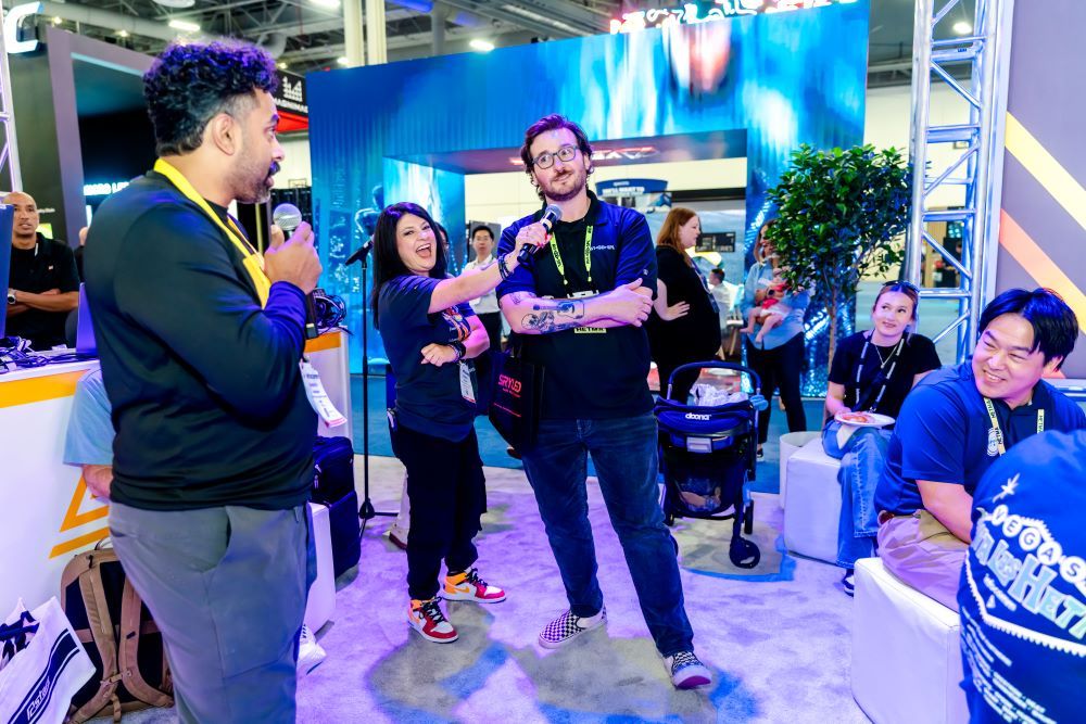 A group of InfoComm attendees laugh together in the Xchange Live booth.