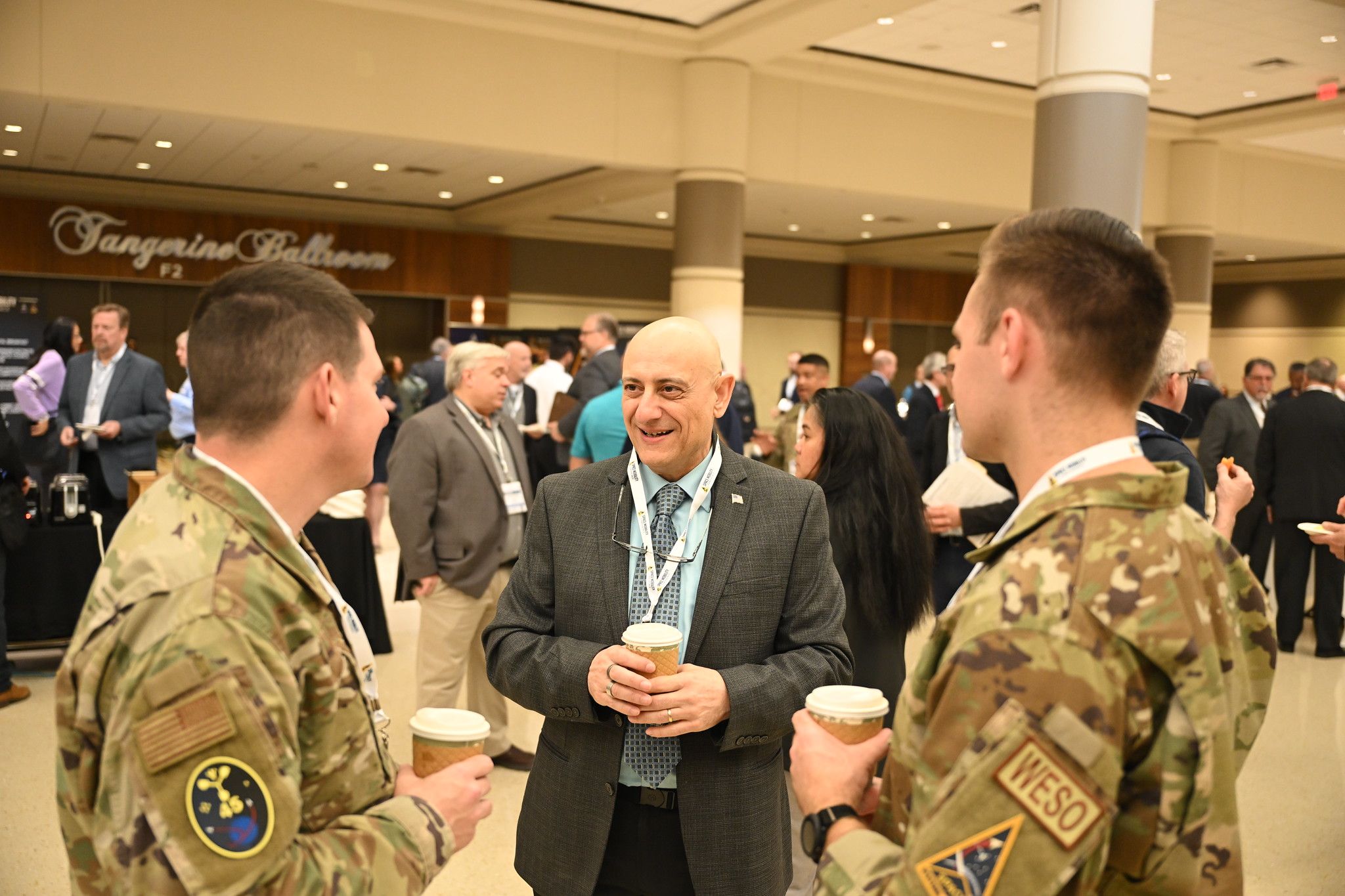 Two men in military uniforms communicating with a man in a suit
