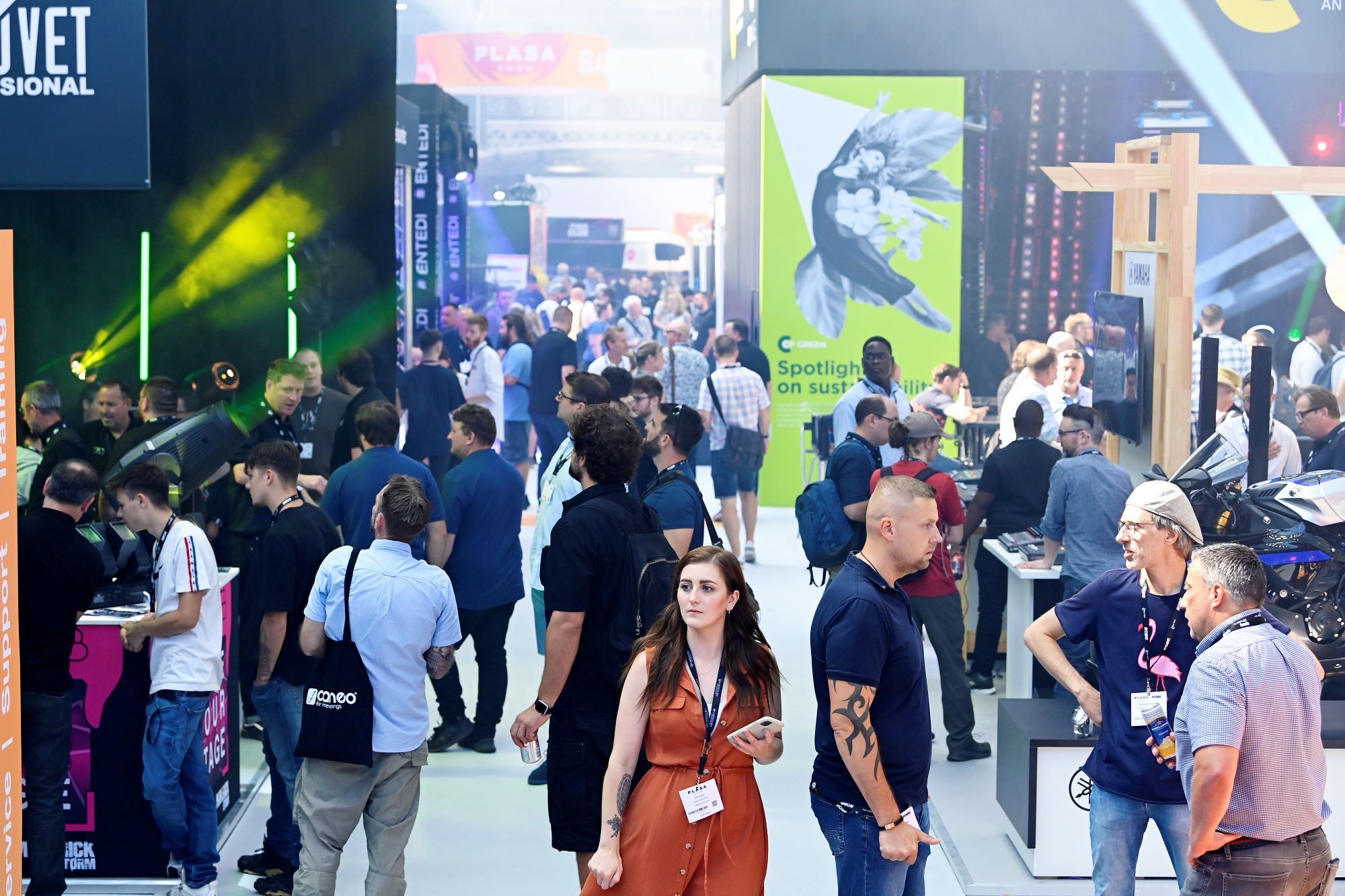 busy plasa show floor isle focusing on woman in orange dress walking through