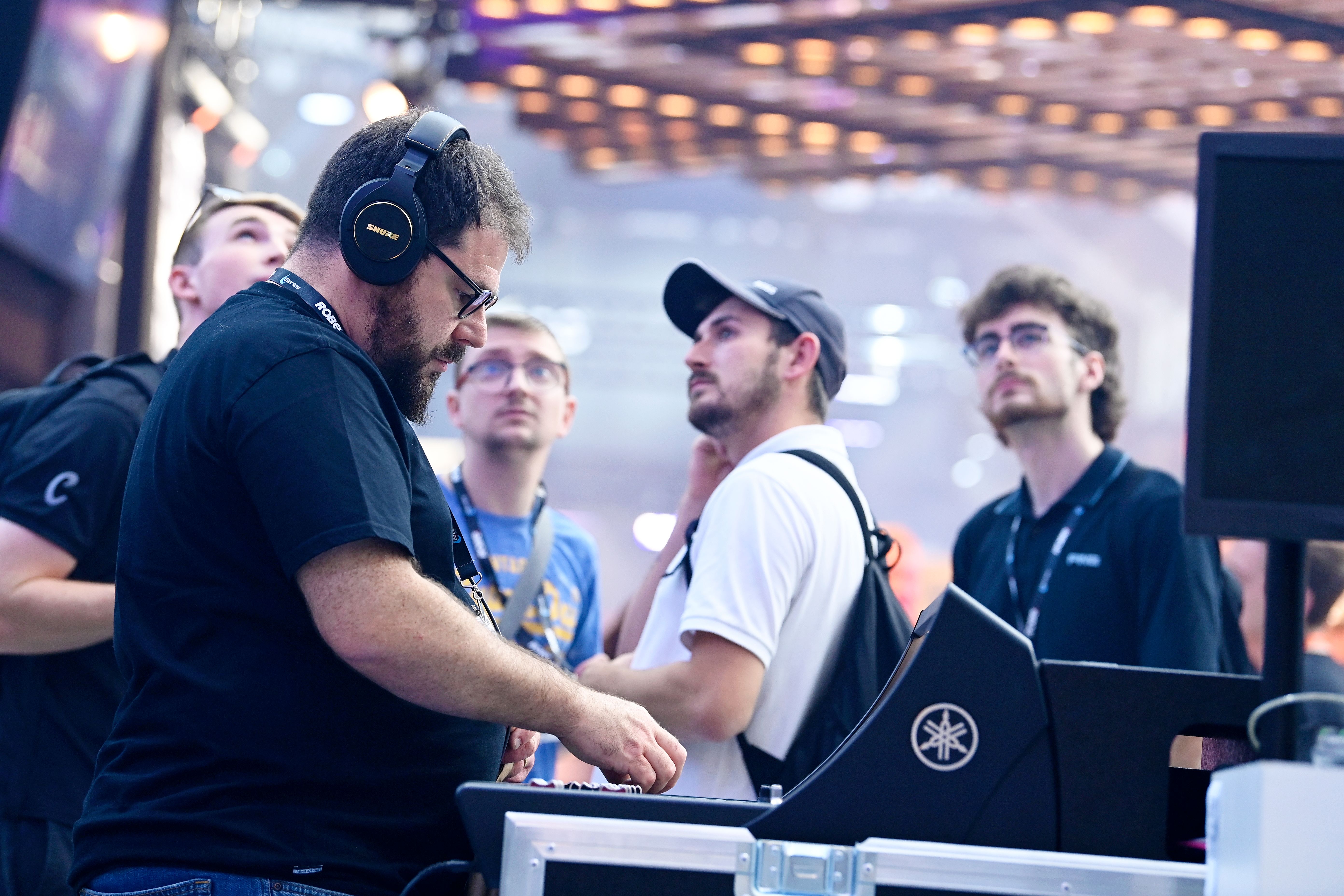man interacting with sound desk wearing shure headphones at plasa show