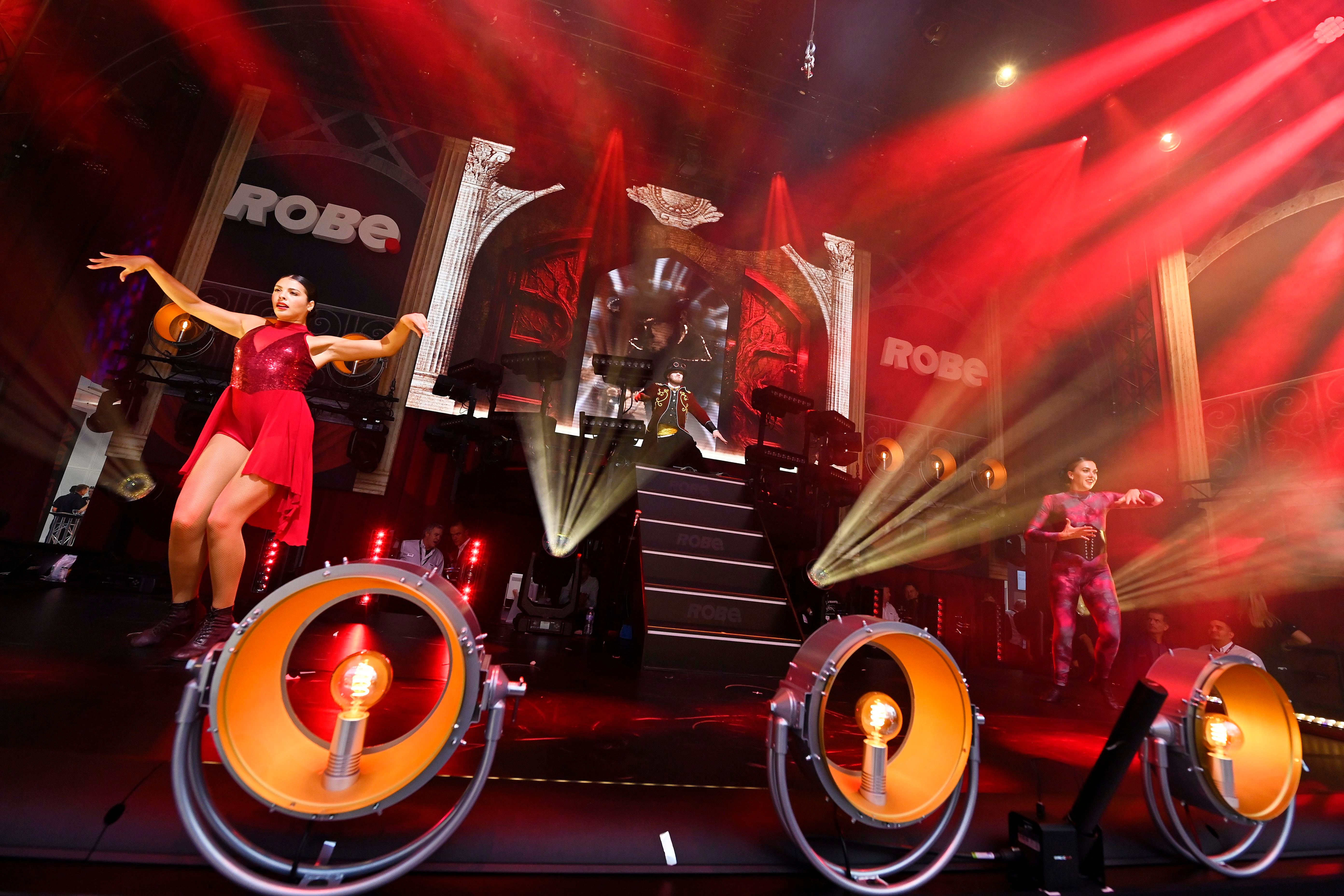 2 female and 1 male dancer performing on stage with strobe lights robe