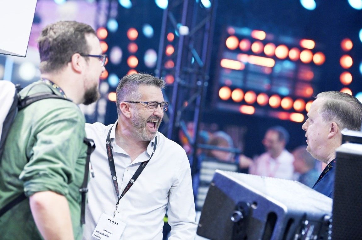 three men laughing in front of a speaker