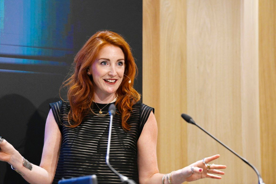 Young woman with bright ginger hair speaking in seminar at plasa show 2024