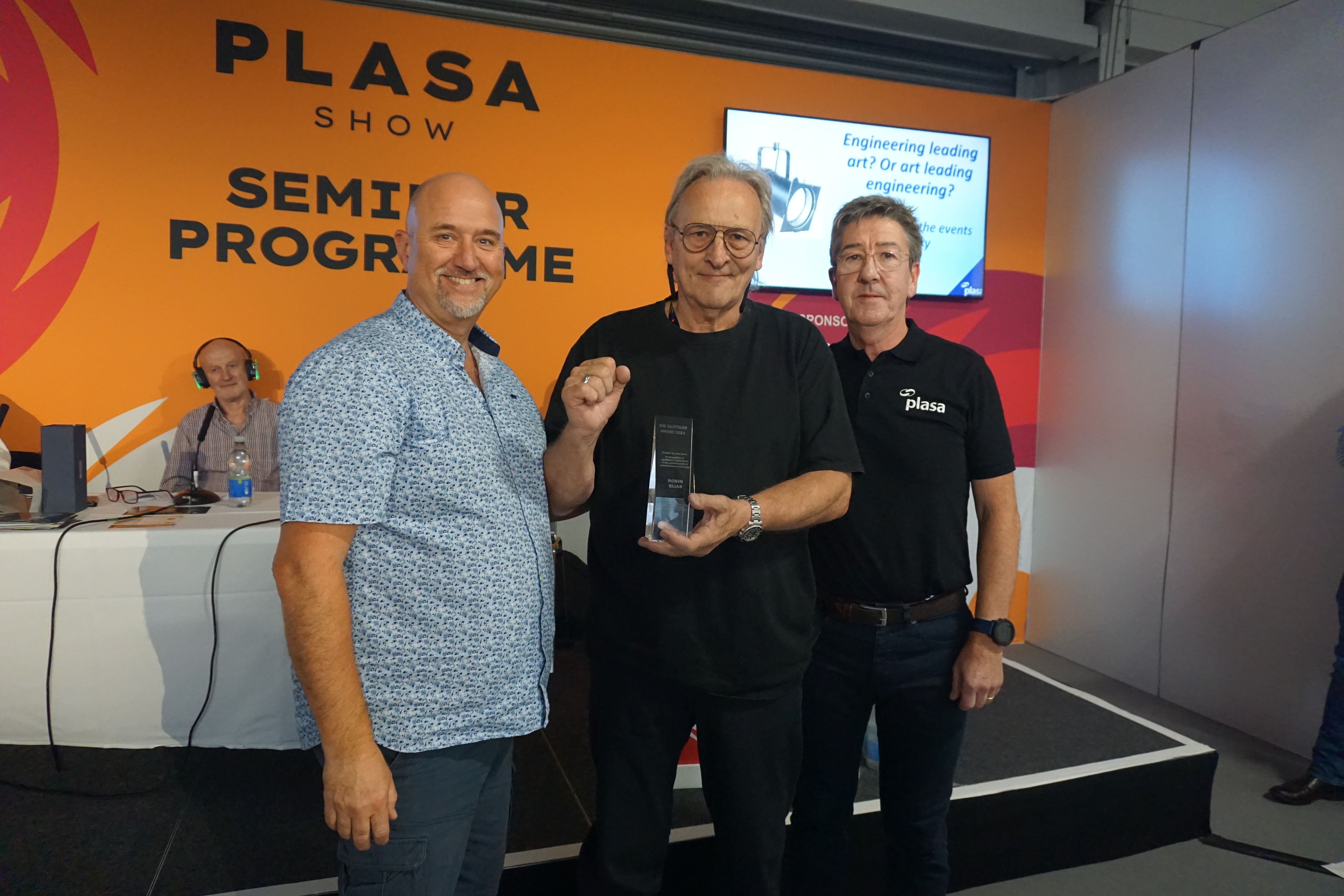 Three men posing with a glass trophy