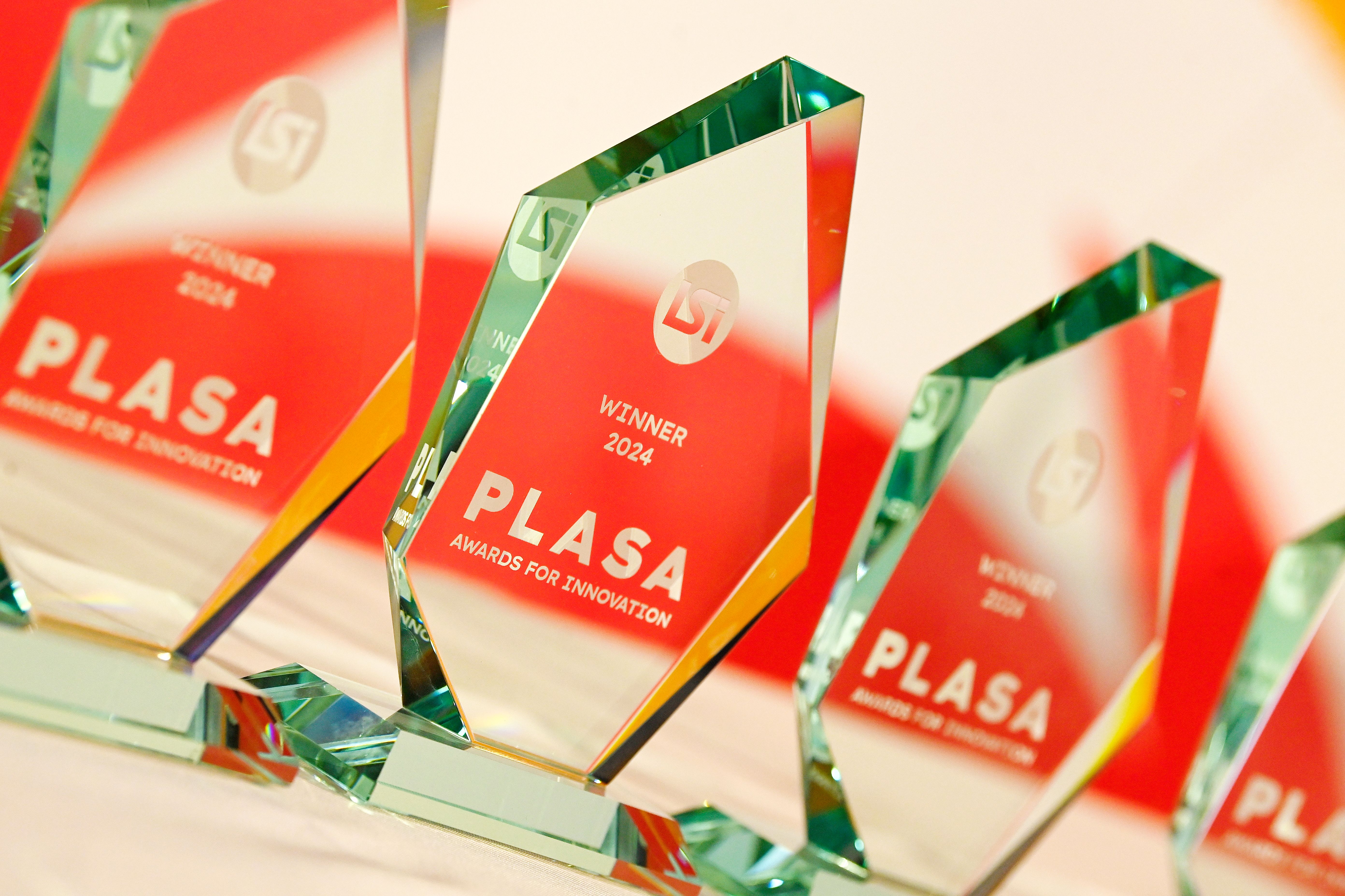 Four PLASA Awards for Innovation glass trophies in a line