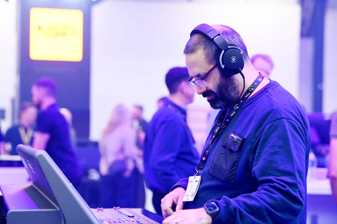 Male visitor in dark top wearing headphones and playing with sound desk