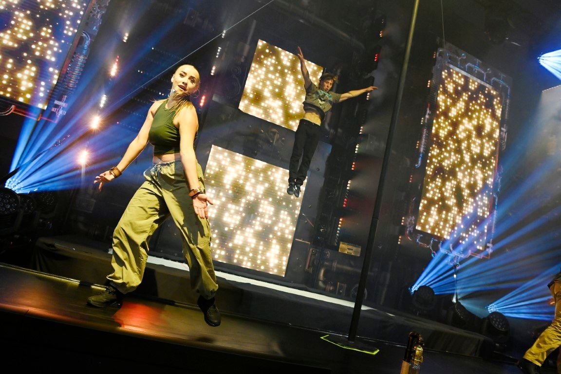 male and female dancers on stage in front of blue beam lights