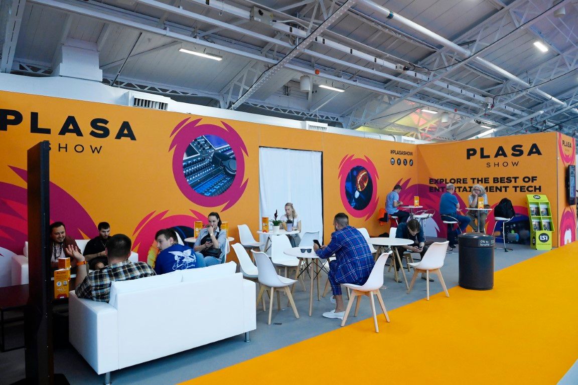 people sitting on sofas and chairs in networking area at trade show