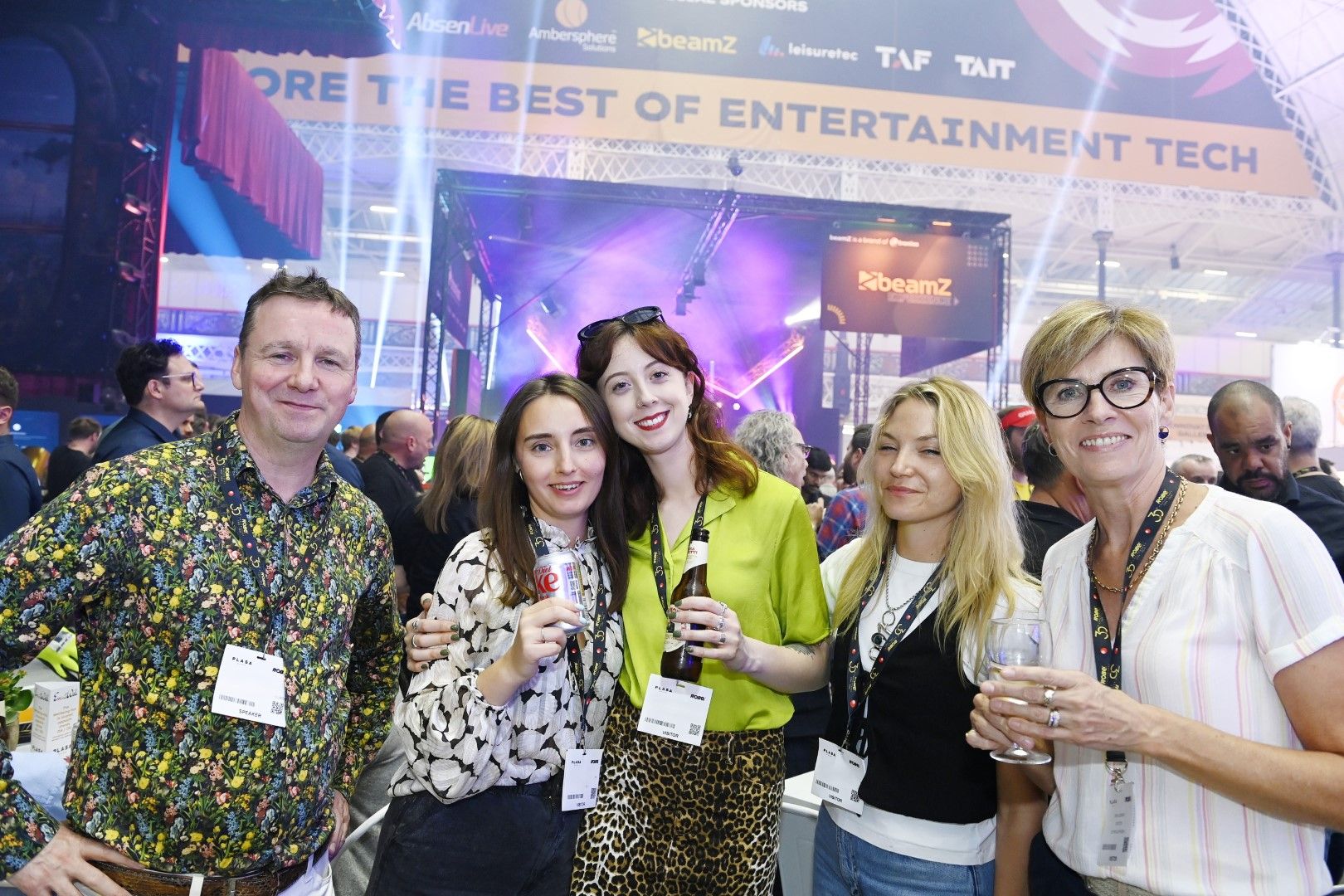 three women and one man posing at a trade show after party