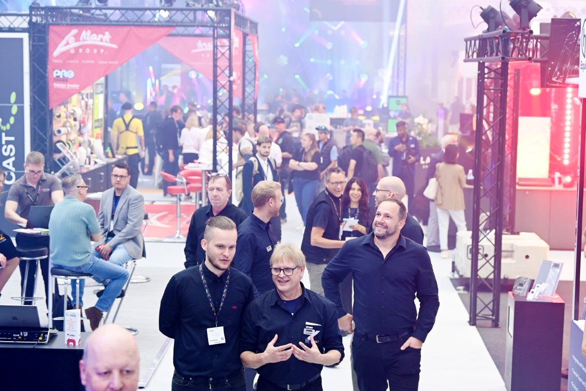 group of men laughing and walking through a tradeshow