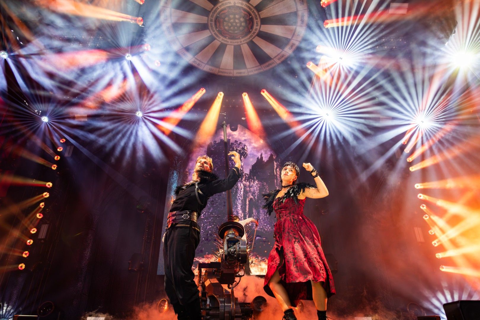Male and female performers dancing under dramatic stage lighting and haze at PLASA Show London 2025, with colourful beams and gobo effects illuminating the stage
