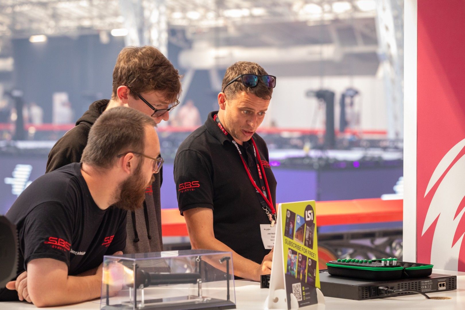 Three men from SBS Events discuss a lighting product display at the LSi Innovation Gallery during PLASA Show London 2025.