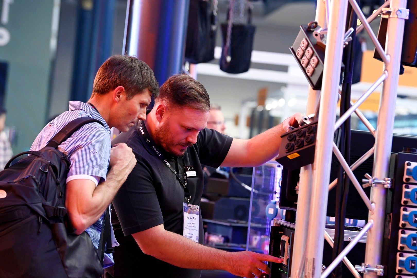 Two male attendees examine professional lighting and power distribution equipment on display at PLASA Show London 2025