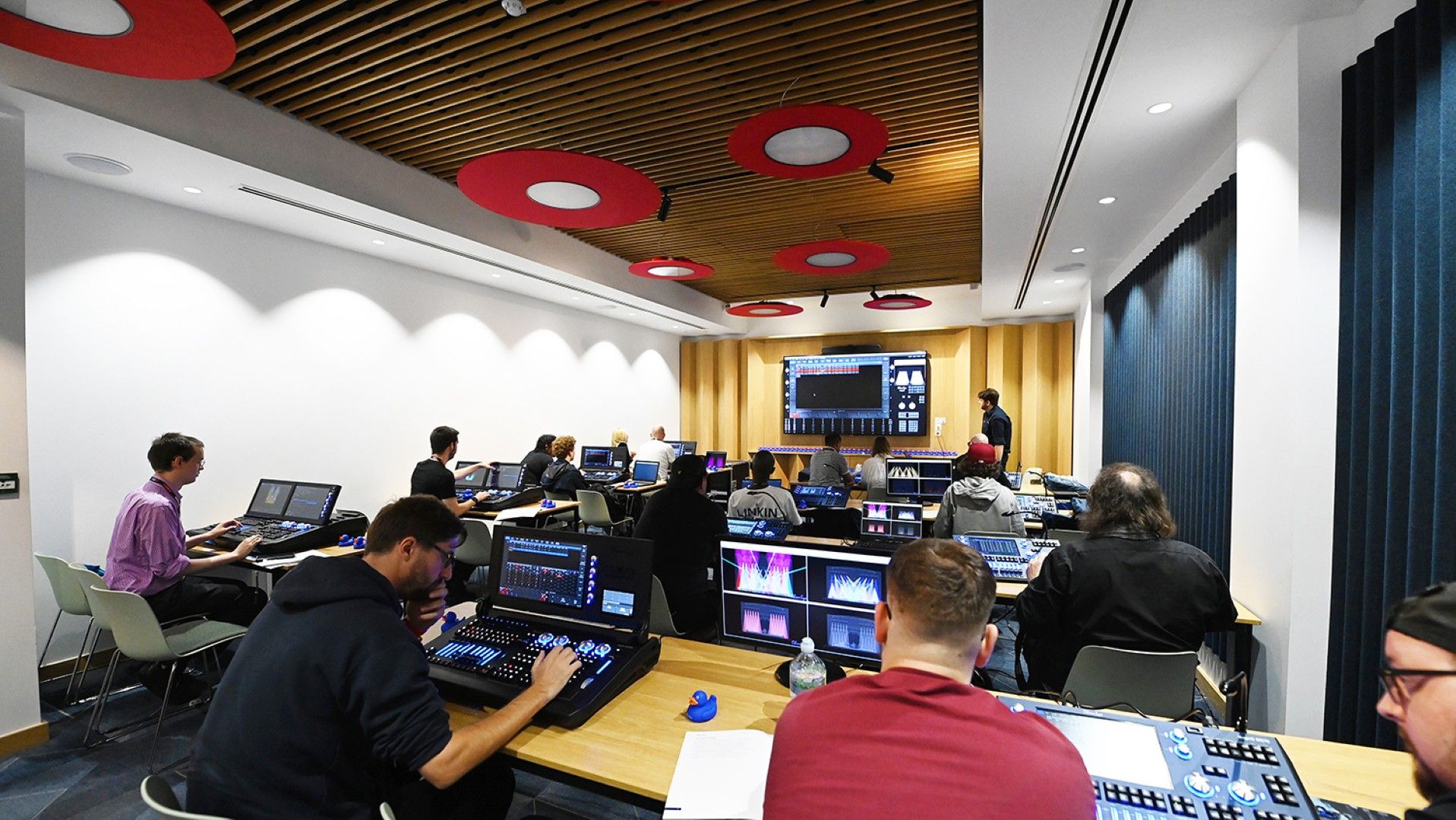 Attendees take part in ChamSys lighting control training at PLASA Show London 2025, working on lighting consoles while following along with the instructor at the front of the room.