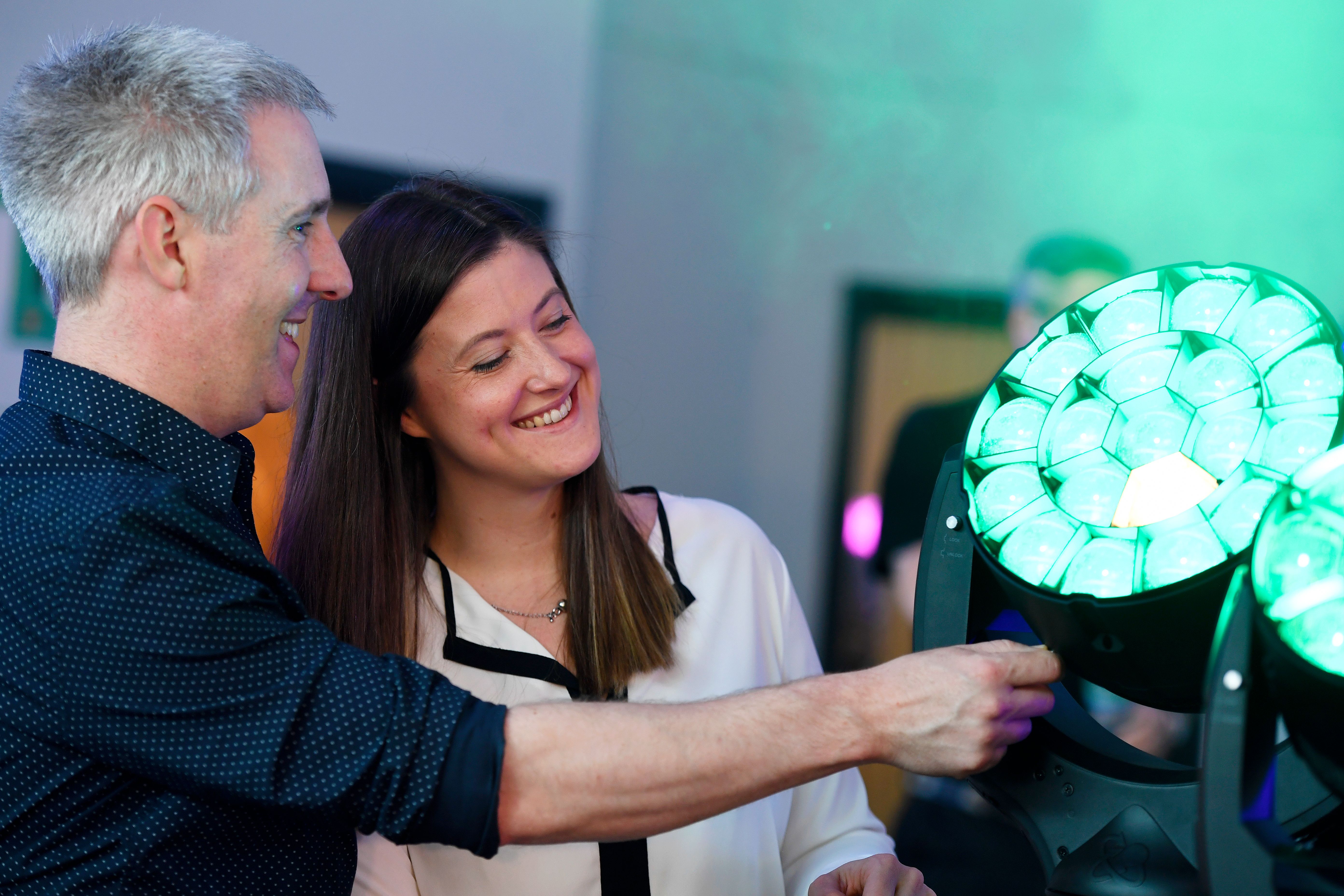Man and woman smiling at a professional green light at a PLASA trade show in Leeds