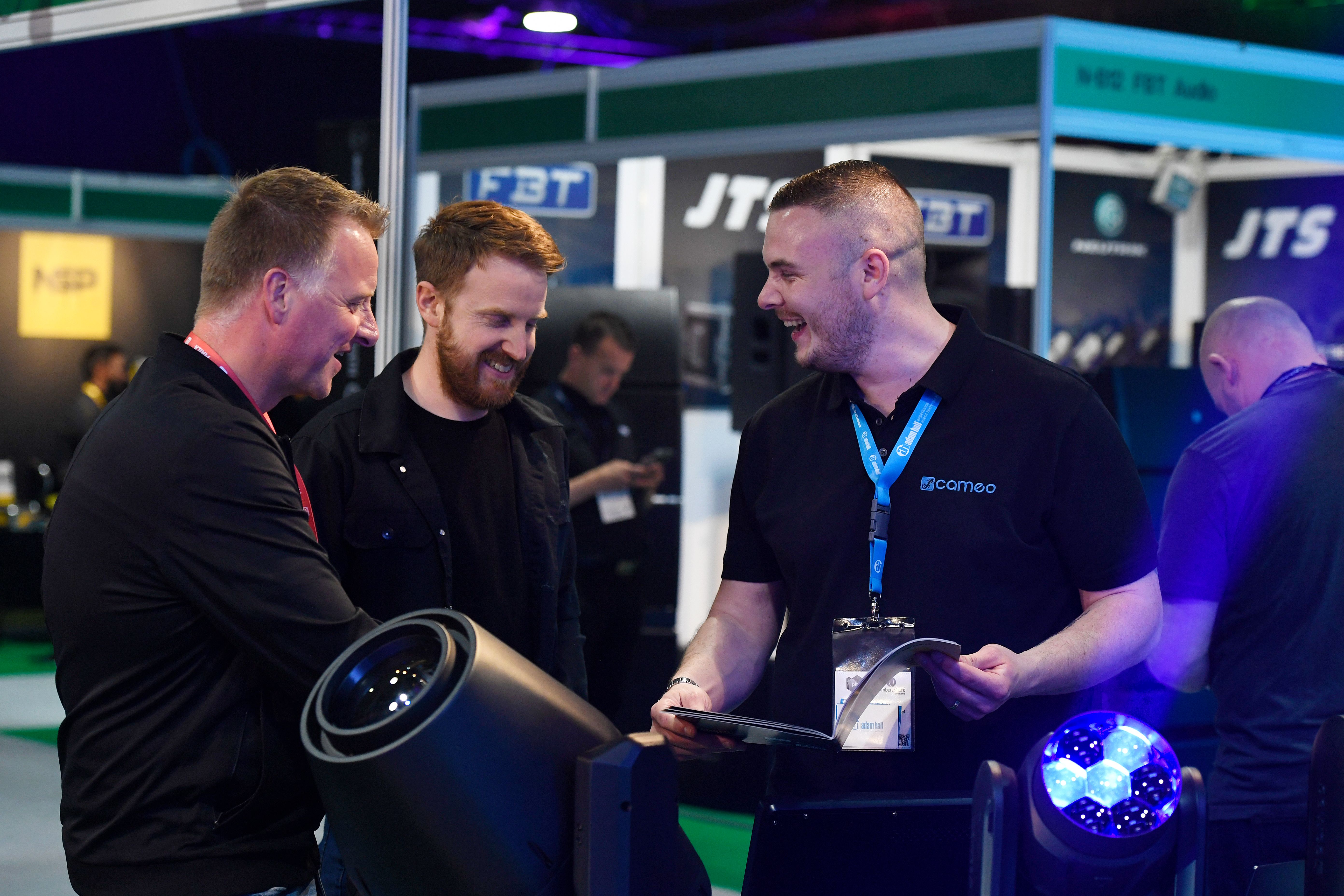 Visitors laughing with Cameo Lighting employee at entertainment technology trade show in Leeds UK