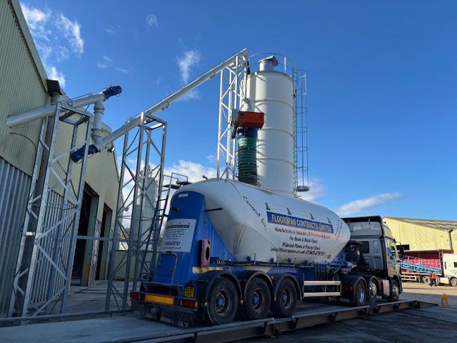 Poggi Model 75 system loading bulk material into a road tanker via enclosed screw conveyors and loading bellows at an industrial site