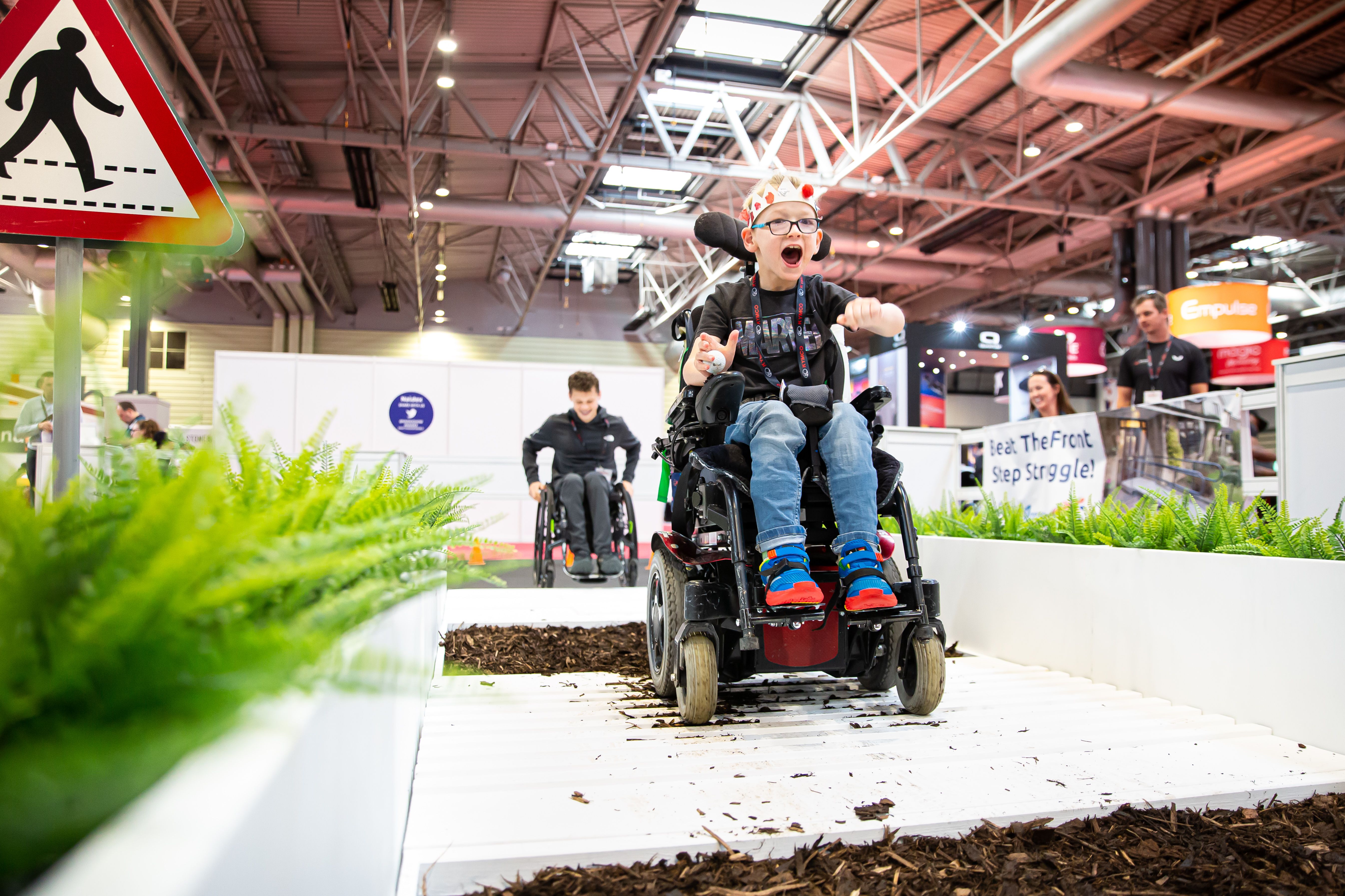 A young boy is on the mobility test track in his wheelchair. 