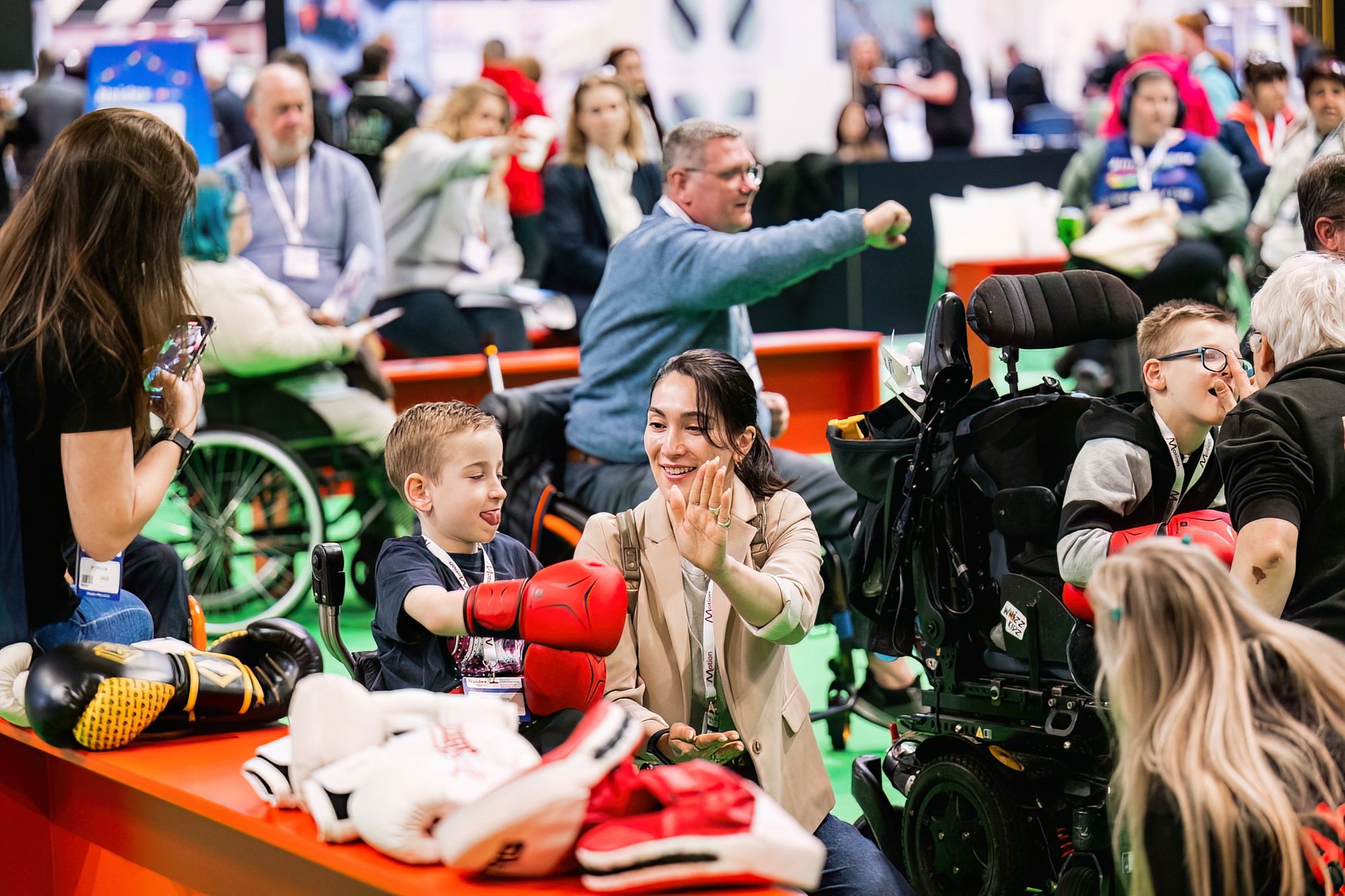 A child is wearing boxing gloves taking part in an activity at the village green at Naidex. 