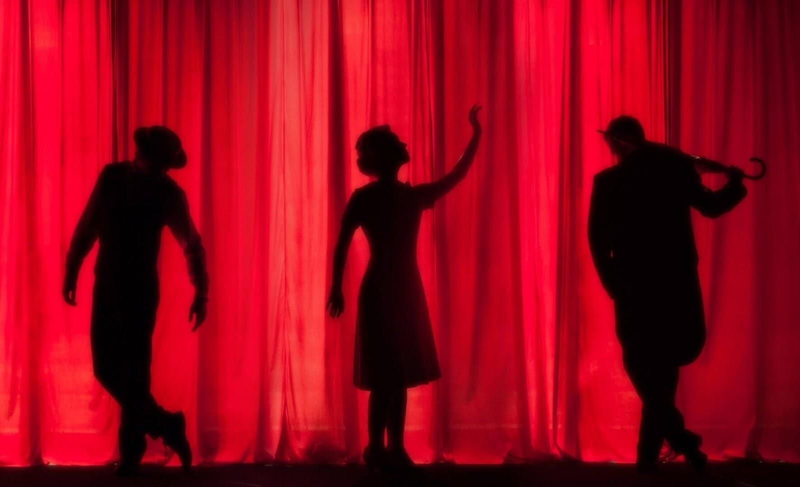 Picture of three silhouettes on a theatre stage