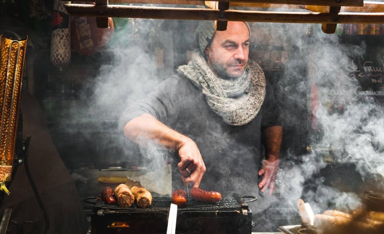 Picture of a man grilling sausages in an outdoor Christmas market