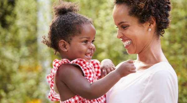 A mother holding her child whilst both laugh.