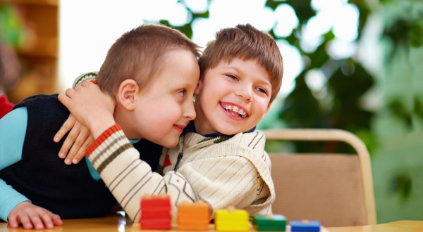 Two children hugging each other and smiling.