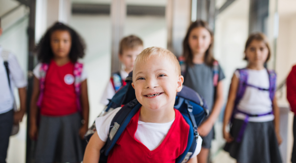 Child smiling with a group of other children blurred in the background.