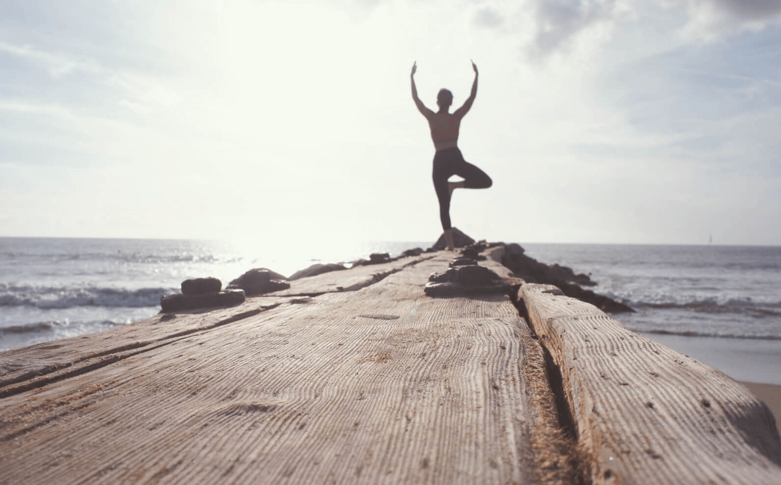 Picture of a woman doing yoga by the ocean.