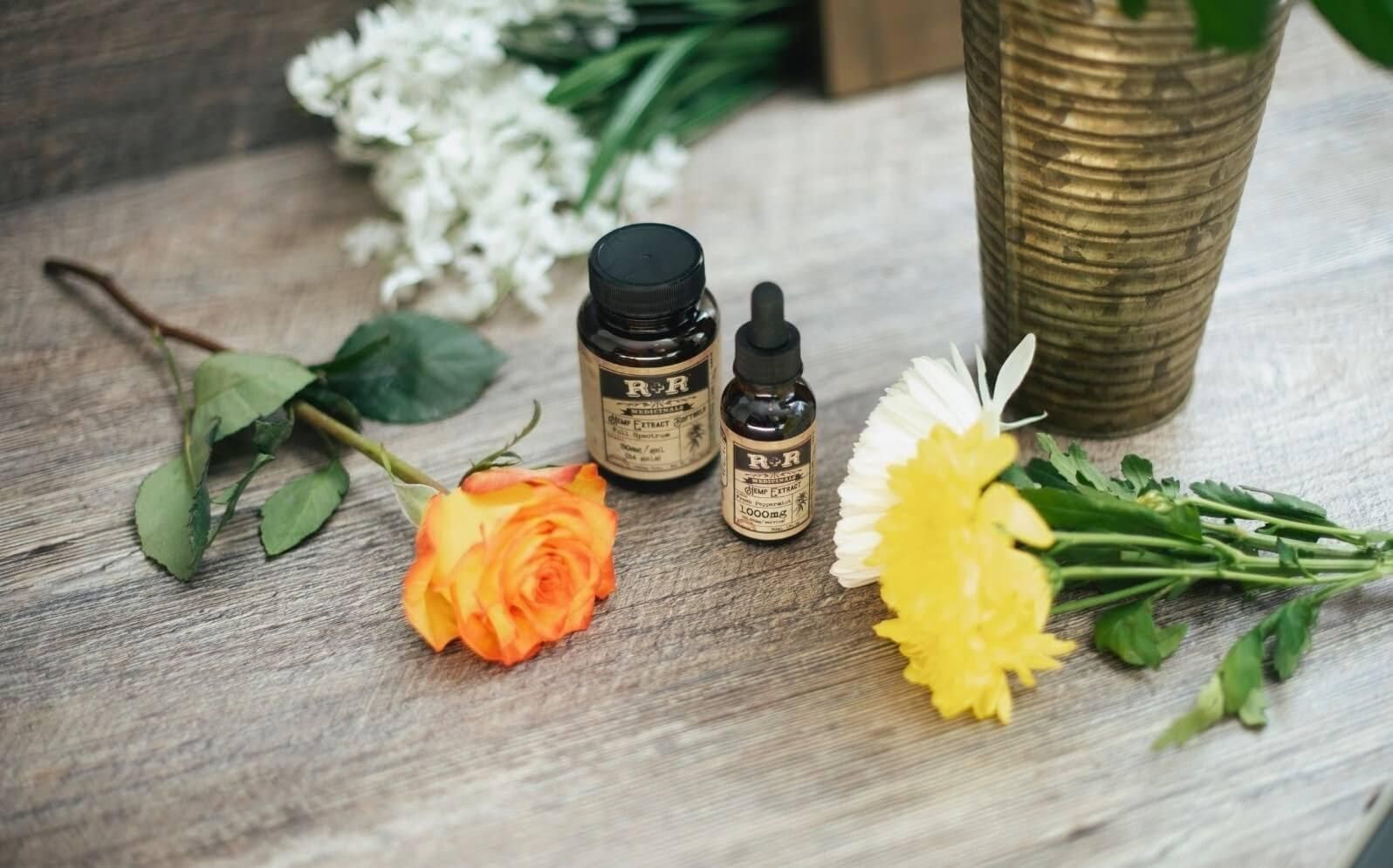 Picture of amber glass bottles on a table with some flowers led on it.