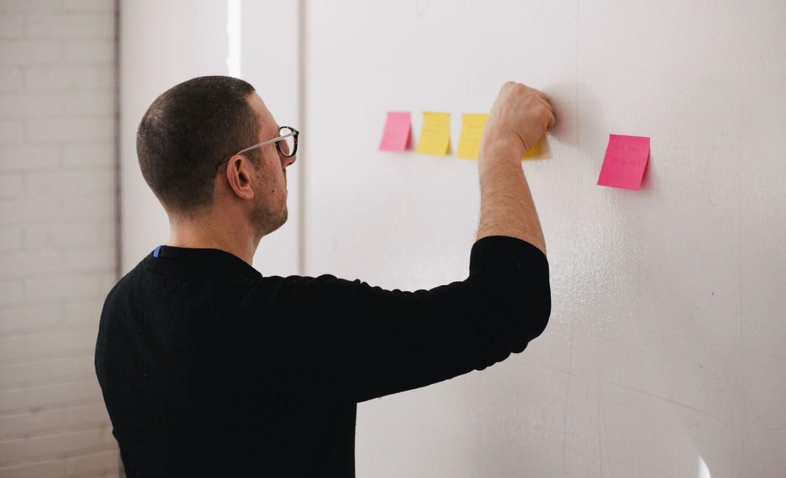 Picture of man sticking sticky notes on a wall