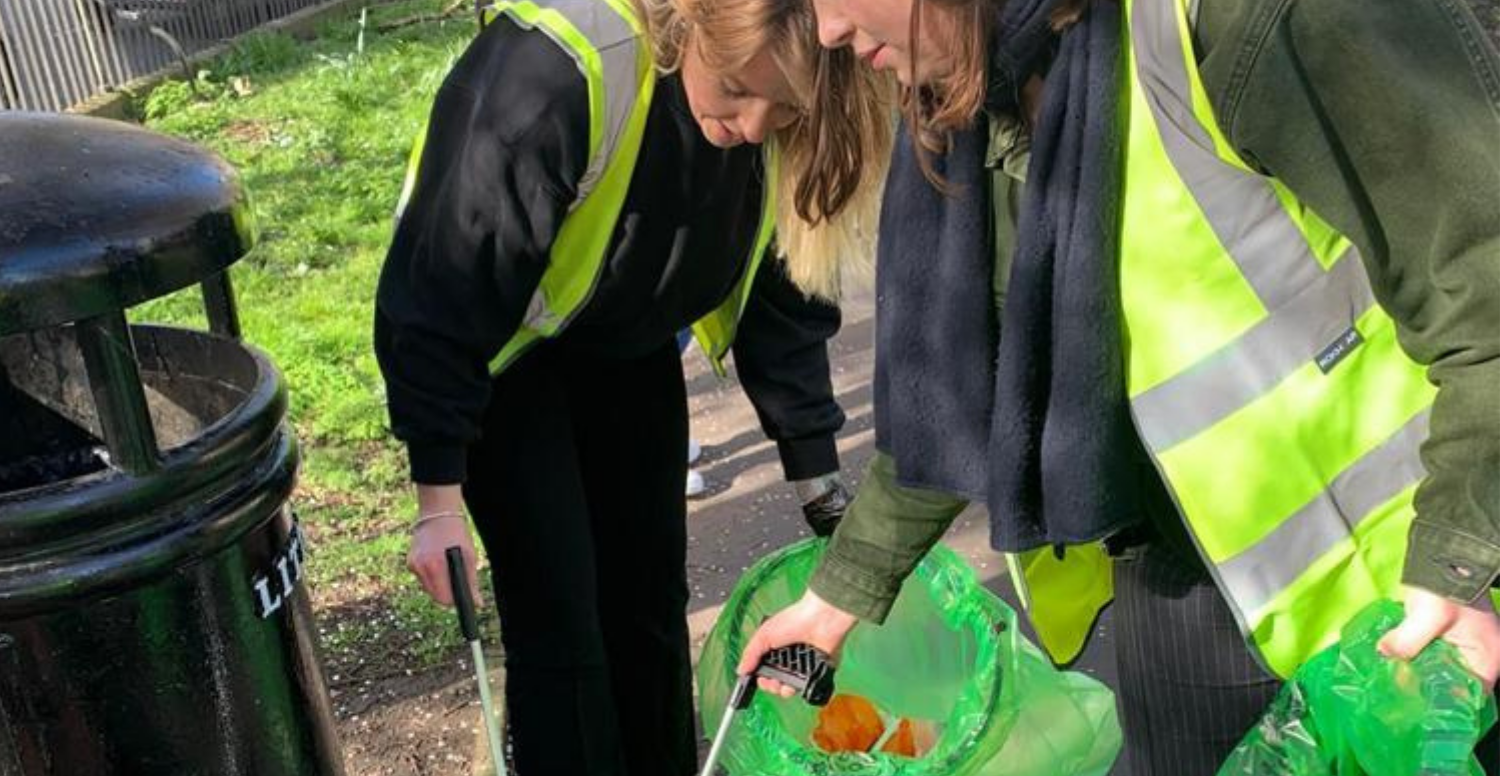 2 women are litter picking wearing high vis jackets 
