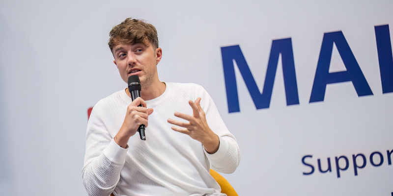Roman Kemp holding a microphone at a past event hosted by Naidex