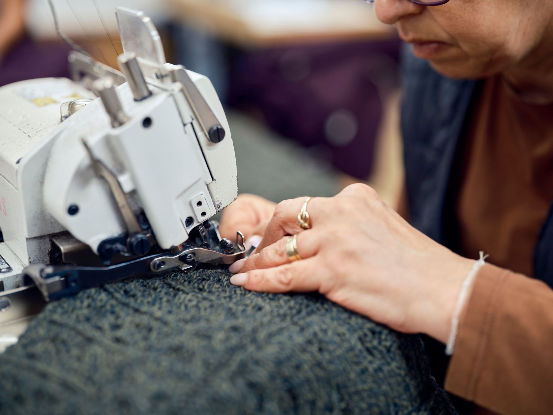 A pair of hands guiding fabric throw a sewing machine