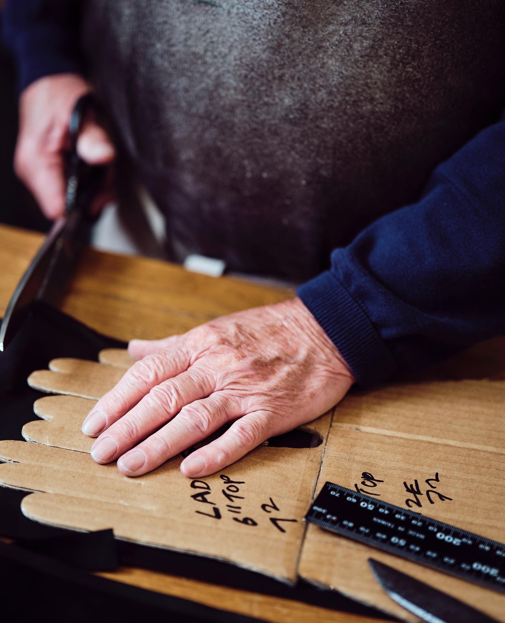 A pair of hands is tracing a glove pattern on cardboard with 