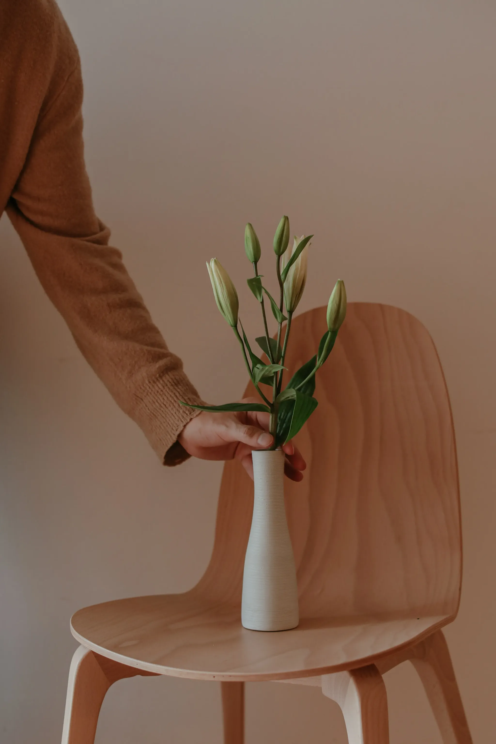 An image of a chair with a stack of book and a vase