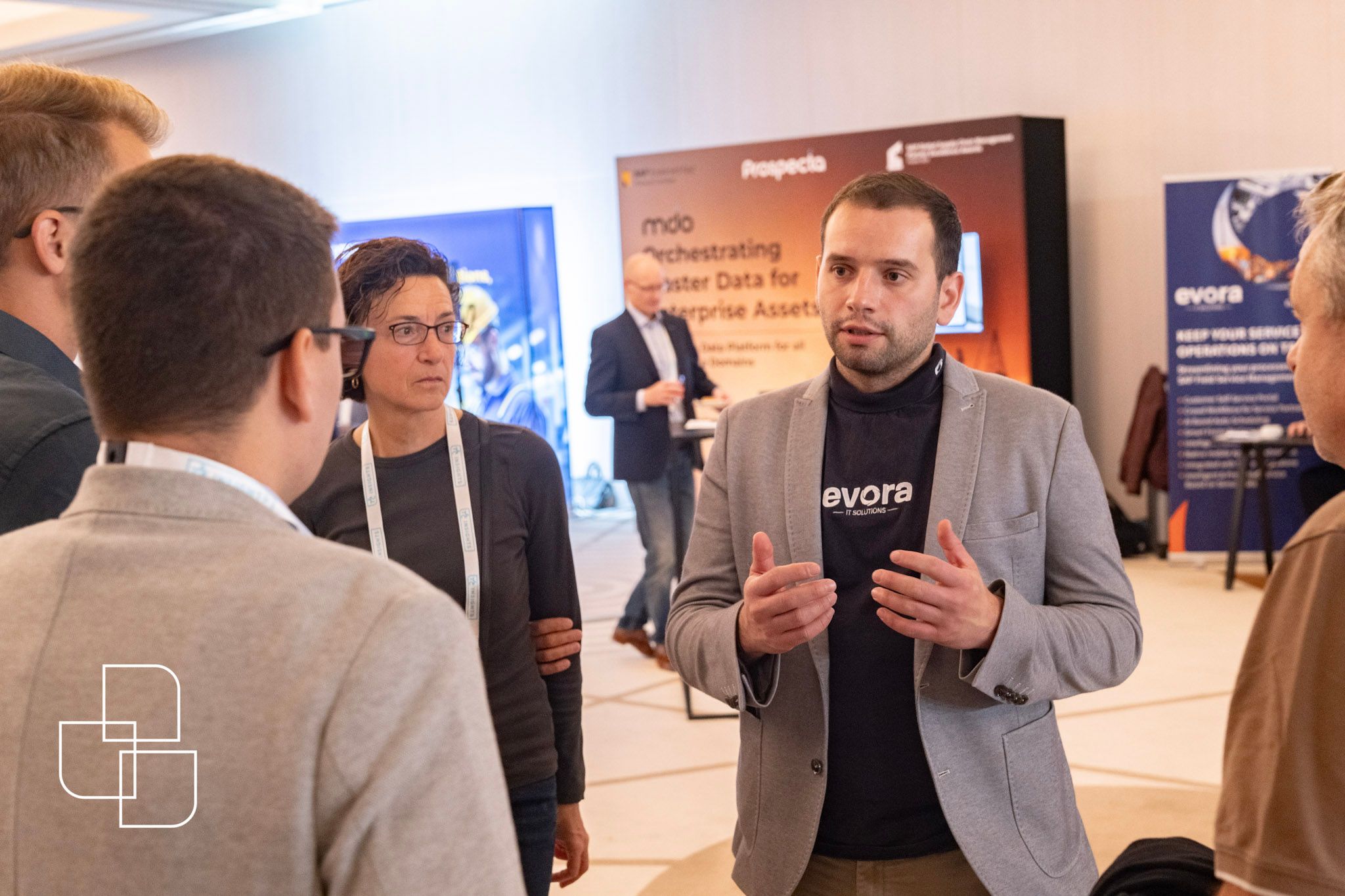 a group of 3 attendees with a sponsor, gathered in a circle talking