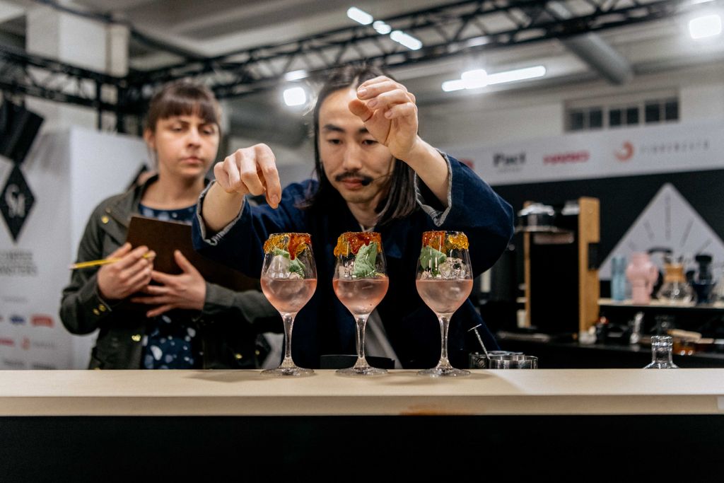 Man pouring cocktail liquid into three glasses