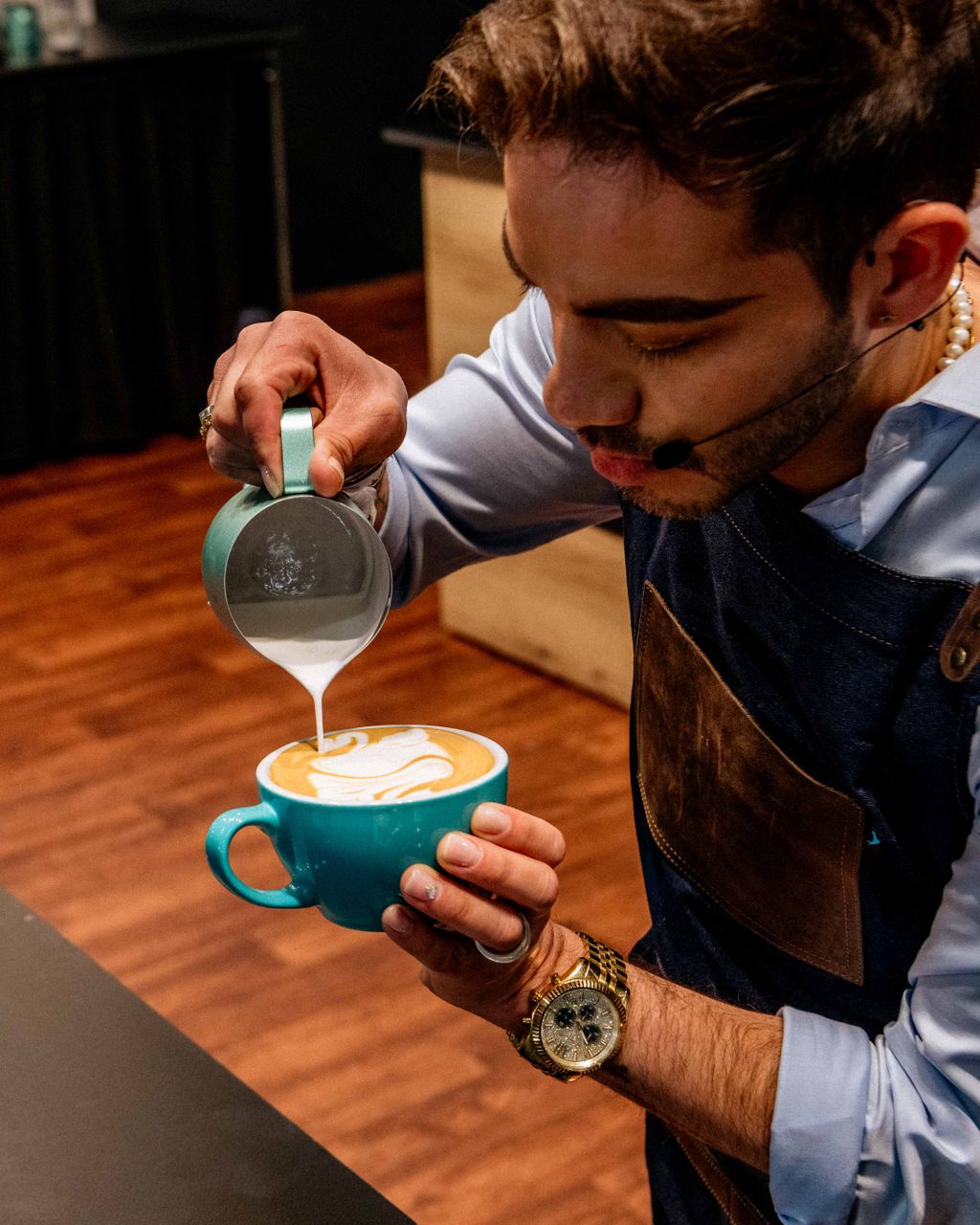 Person creating coffee art by pouring milk into cup