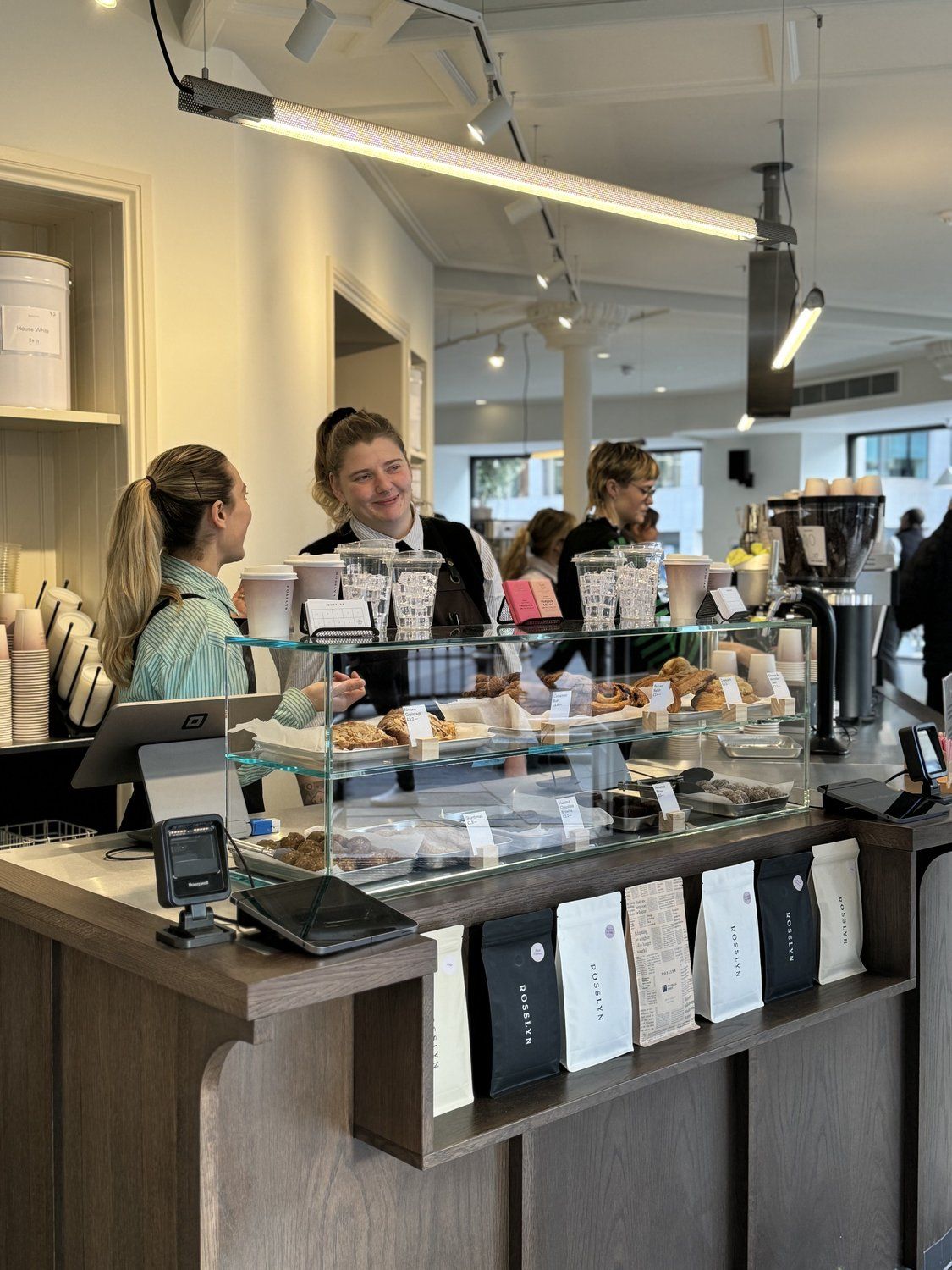 Two baristas serving customers behind a coffee shop counter
