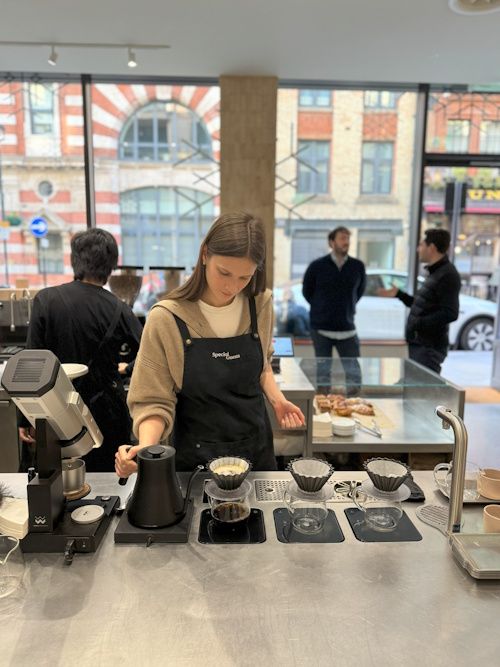 Barista pouring milk into a cup behind the bar
